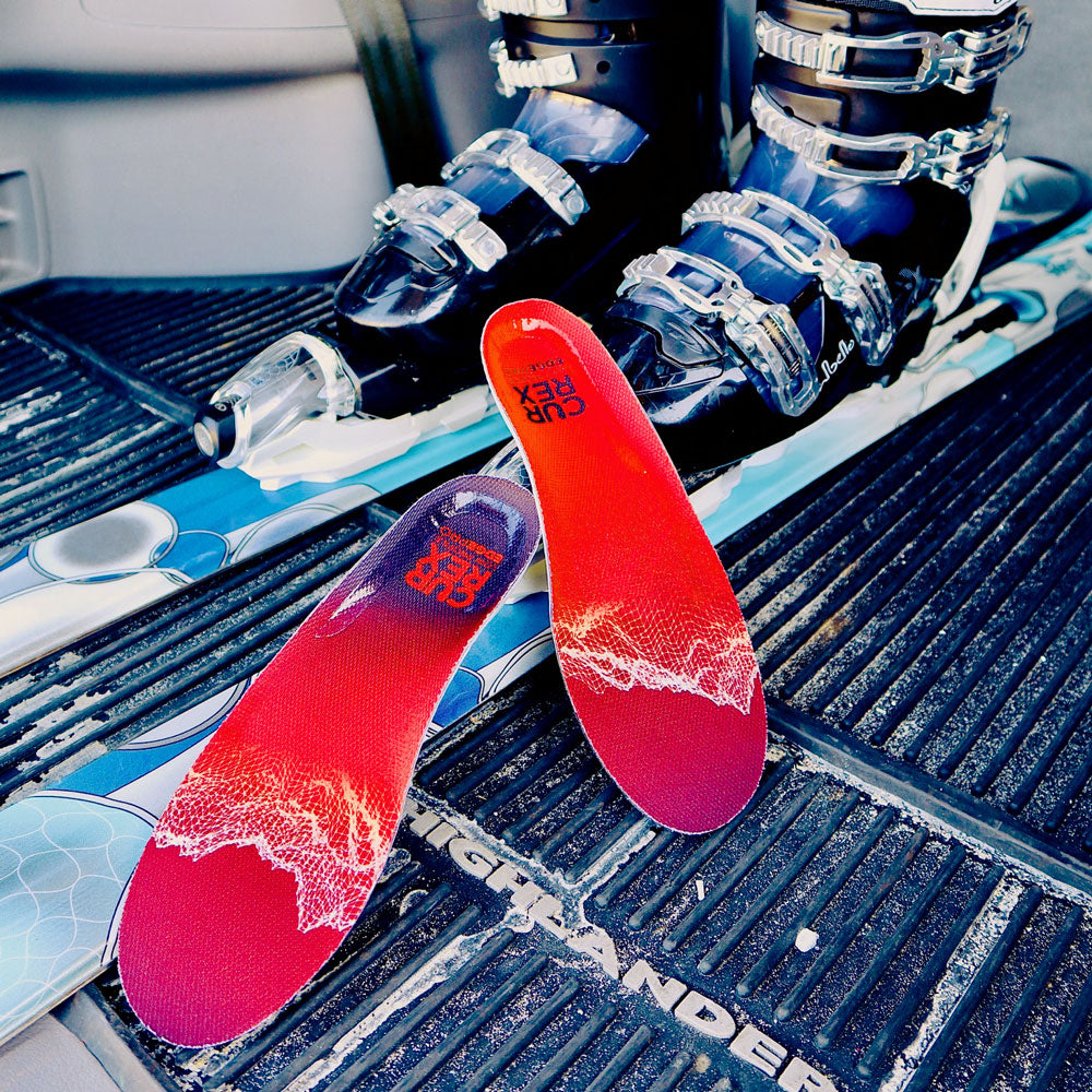 Pair of red low profile CURREX EDGEPRO insoles next to skis and ski boots #1-wahle-dein-profil_low