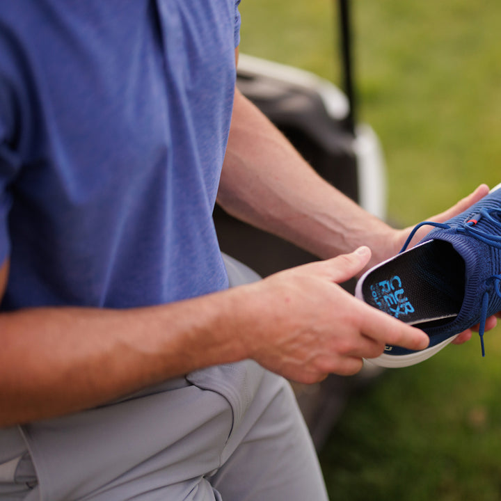 Man placing CURREX GOLFPRO insoles into shoe at the golf course #1-wahle-dein-profil_low