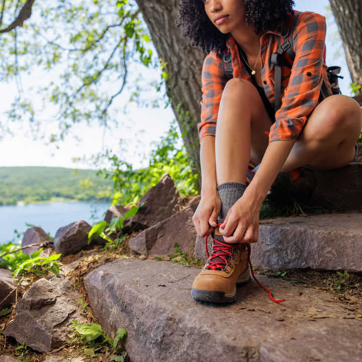 Woman taking break from hiking in the woods, tying her hiking boots #1-wahle-dein-profil_high